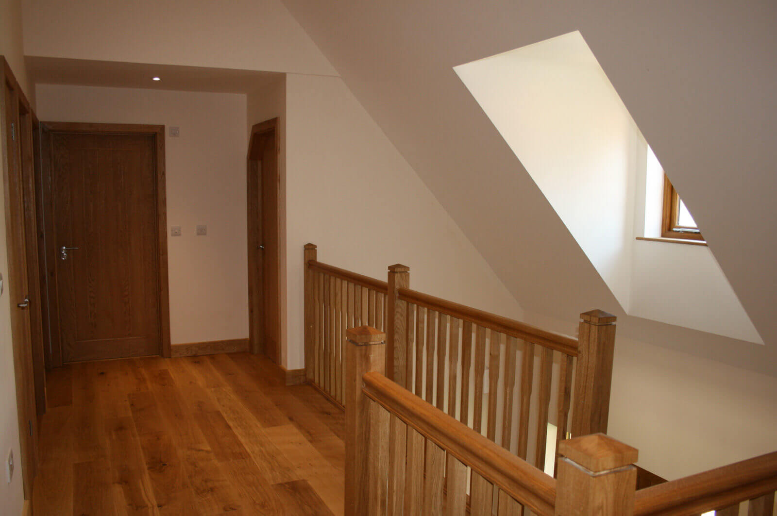 Hard wood floors of hallway by staircase on first floor.